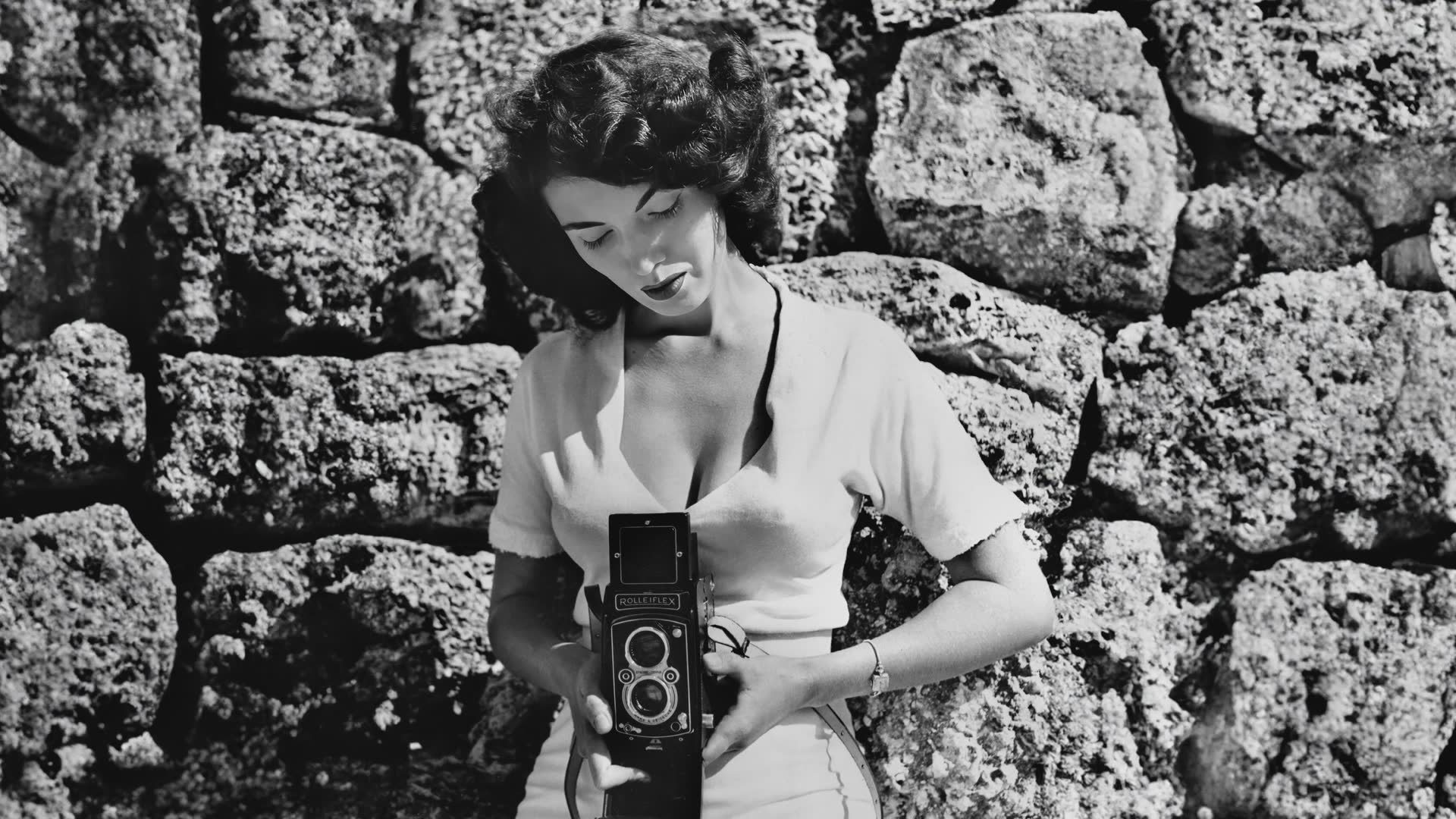 black-and-white photo of photographer Bunny Yeager taking a self-portrait with a midcentury camera