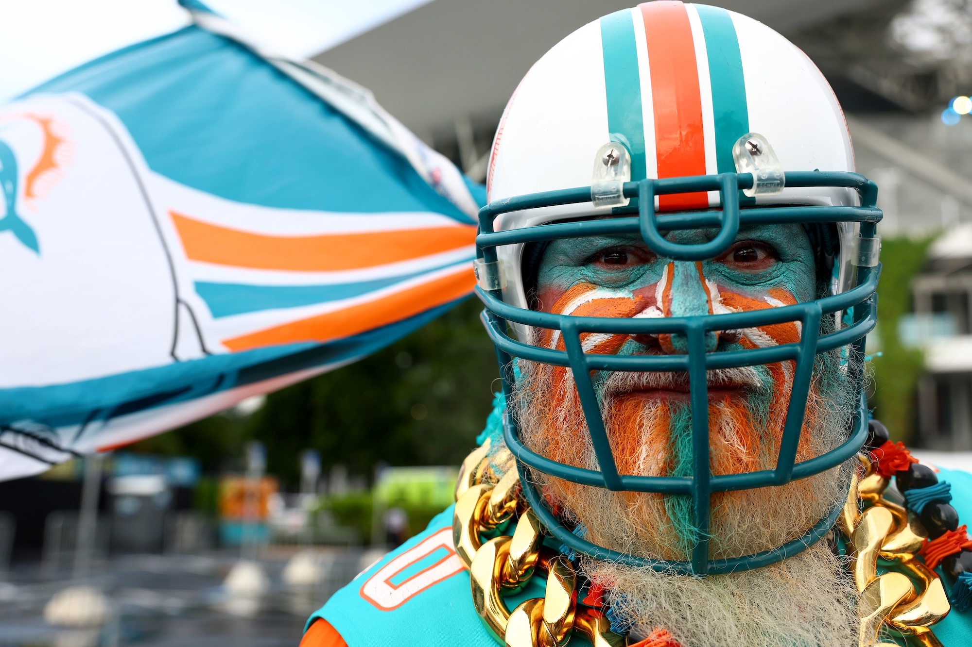Helmeted Miami Dolphins fan in full, face-painted, huge gold-chained regalia