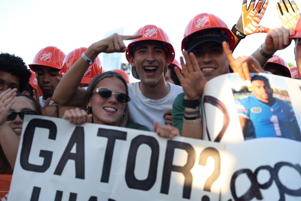 UM fans in Home Depot helmets hold up a sign reading "Gator?"