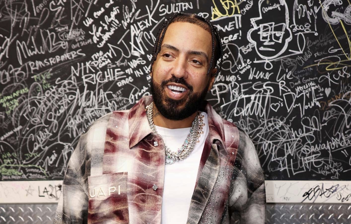 rapper French Montana standing in front of a graffitied wall