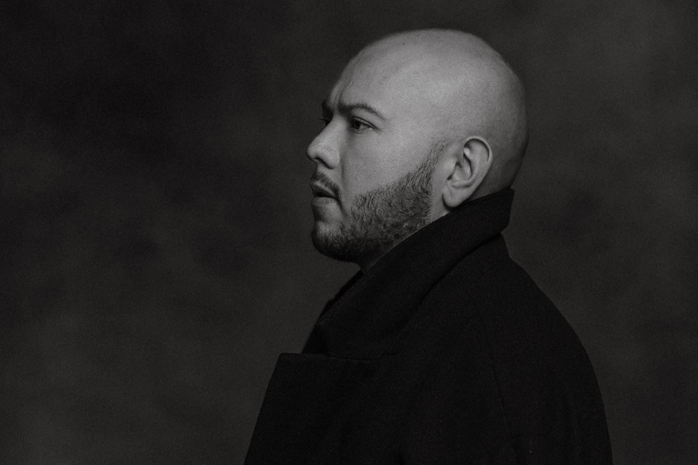 Black and white headshot of a bold man.