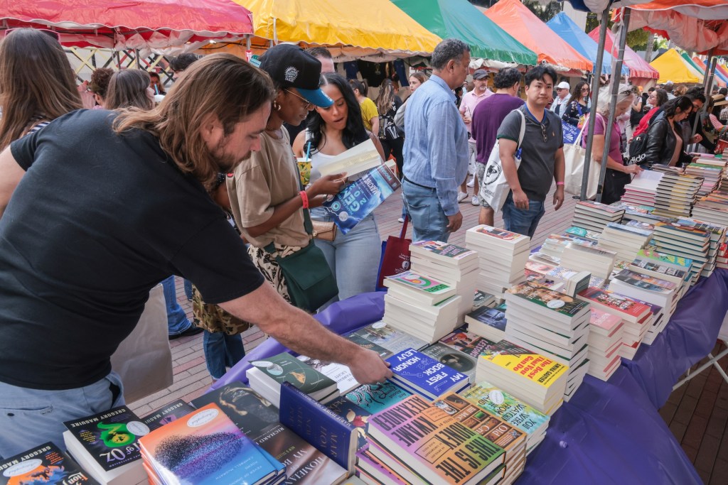people look through books beneath tents at an outdoor book fair