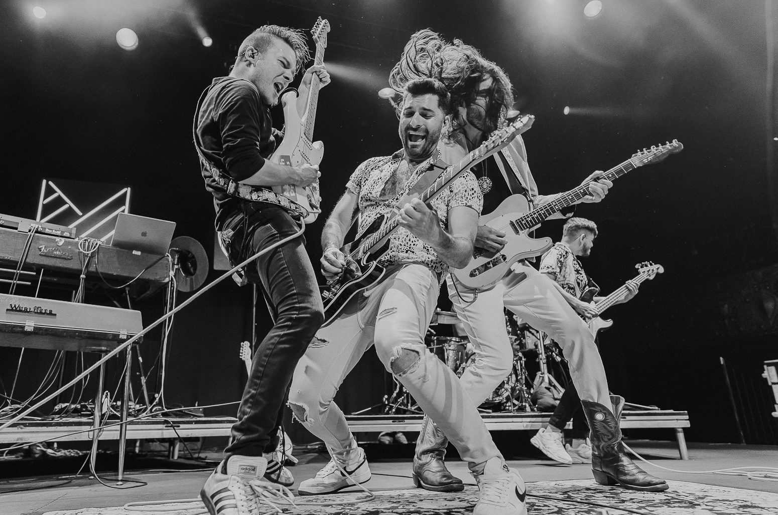 A black and white photo of a rock band performing on stage.