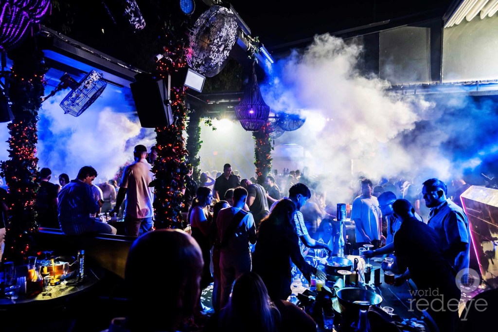 a packed nightclub with revelers lit in blue light
