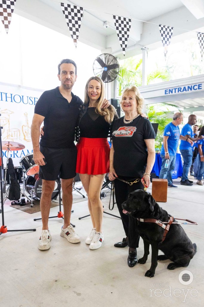 three people pose with a service dog