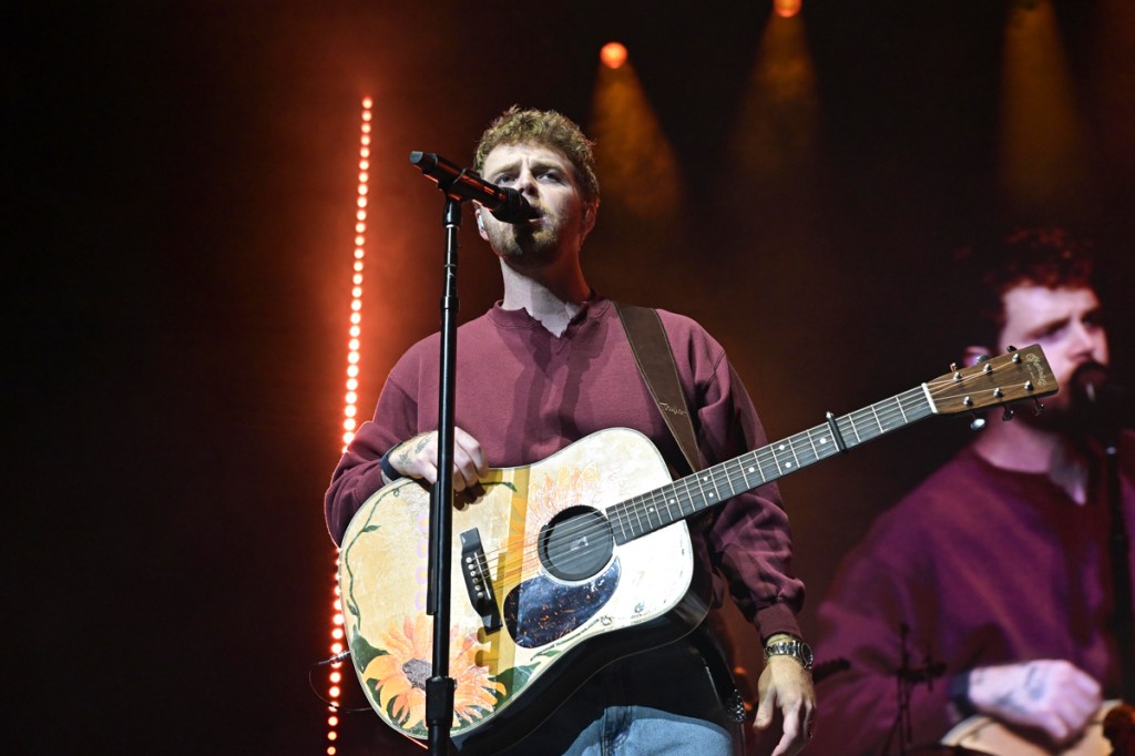 A picture of a man on stage with an acoustic guitar.