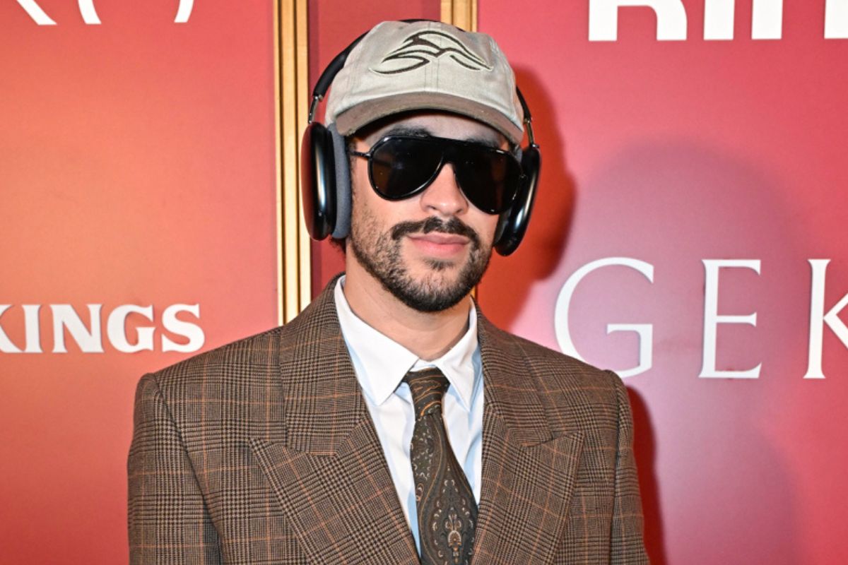 Bad Bunny wearing a brown suit posing for the camera.