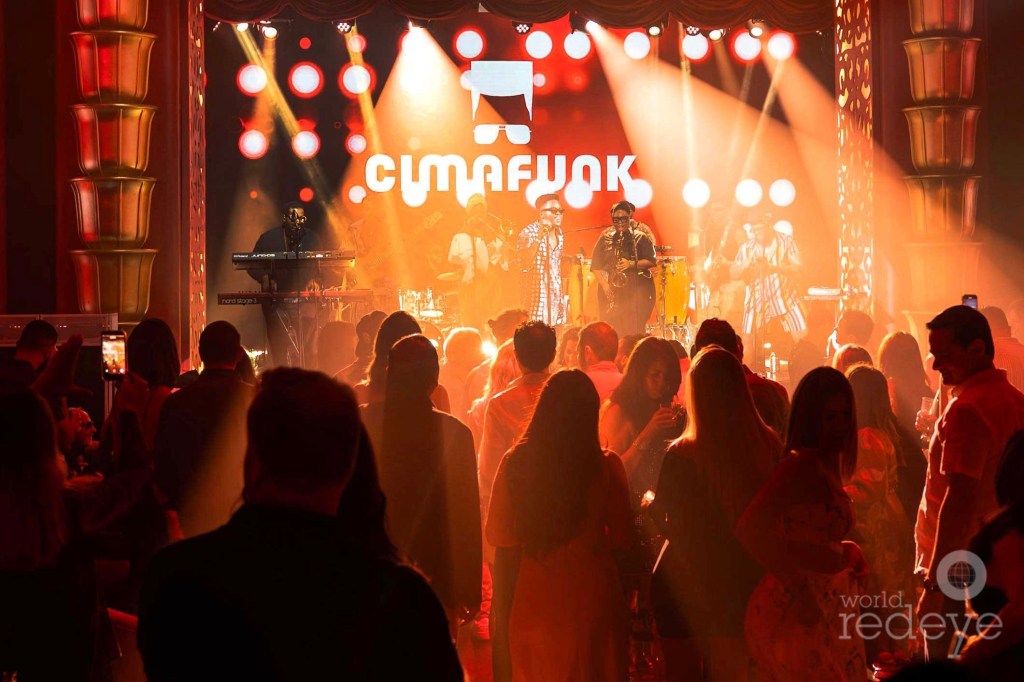 a band plays onstage in front of a cloud under orange stage lighting