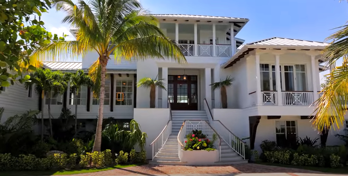 Front entrance of two-story White mansion with palm trees on the left side