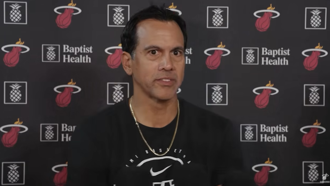 Miami Head Coach Erik Spoelstra Speaks to media. He is wearing gold chain and black long sleeve. He is standing in front of Miami Heat and Baptist Health screen.