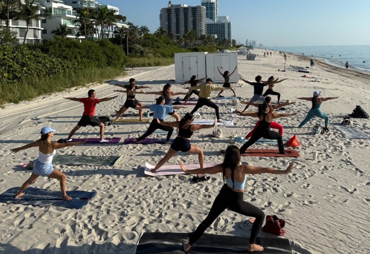 a group of people does yoga on the shores of a beach