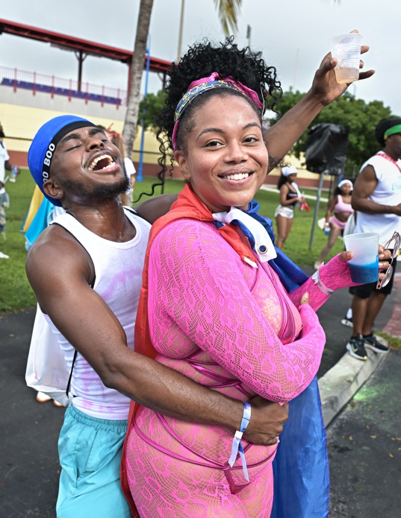 a man in a white tee and durag embraces a woman in a pink fishnet outfit