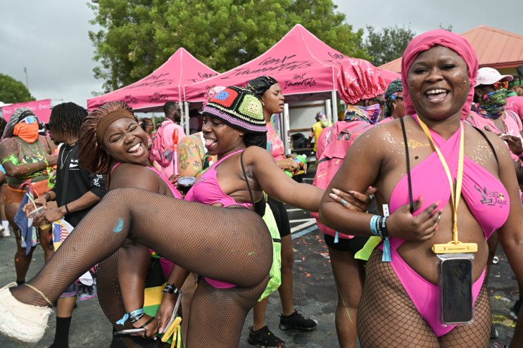 three women in pink festival outfits; two dance with each other