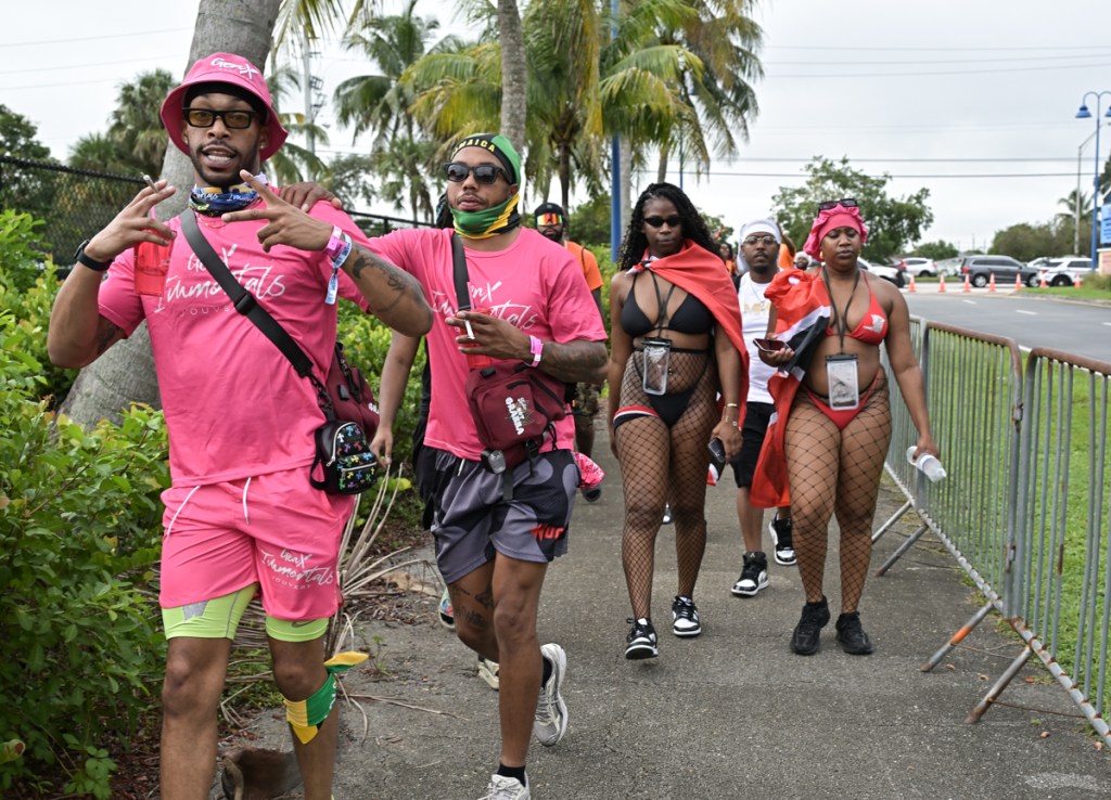 people dressed in festival clothing walk along a barricade