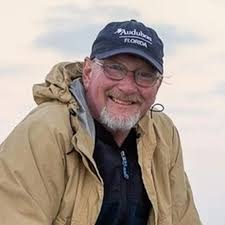 photo of a smiling, bespectacled man wearing a tan parka and an Audubon Florida ballcap