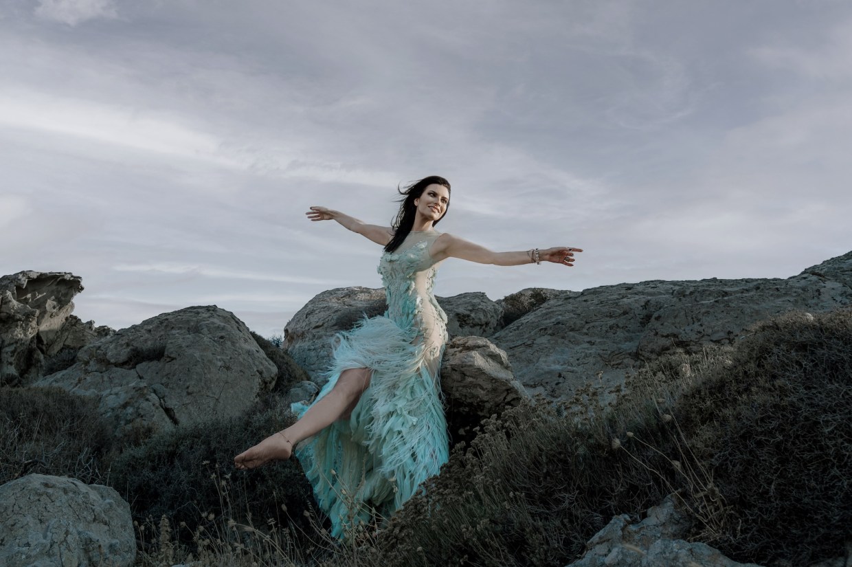 Picture of a woman sitting on a rock wearing a light blue dress.