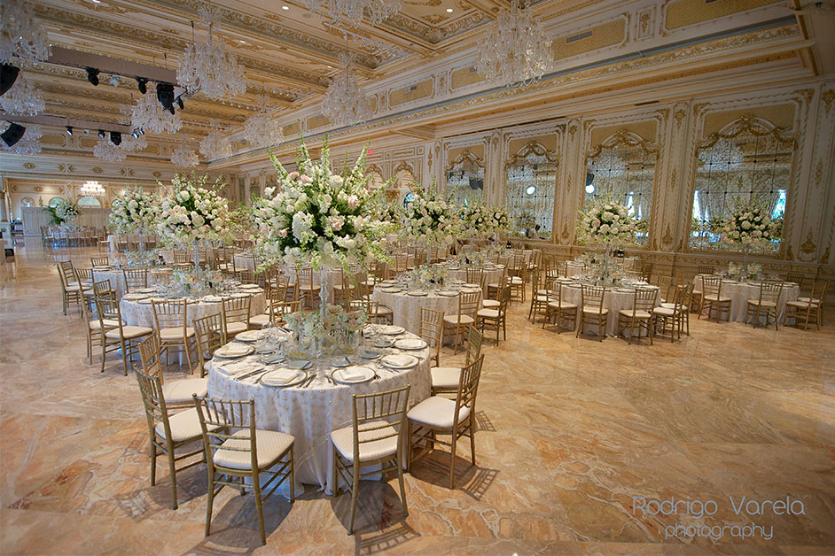 round wedding tables sit in the center of an ornate ballroom