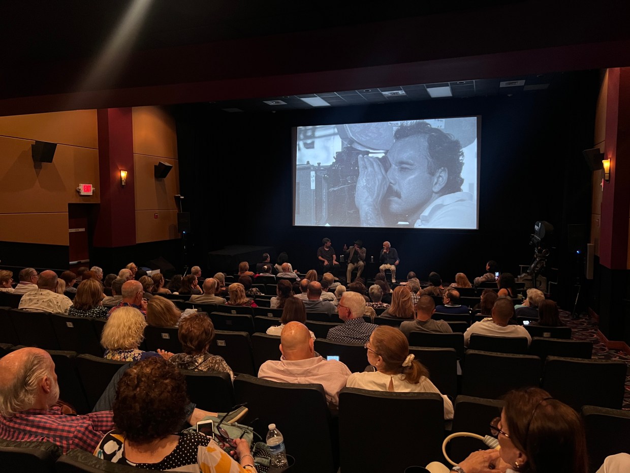 an audience looking at a screen with a black-and-white film