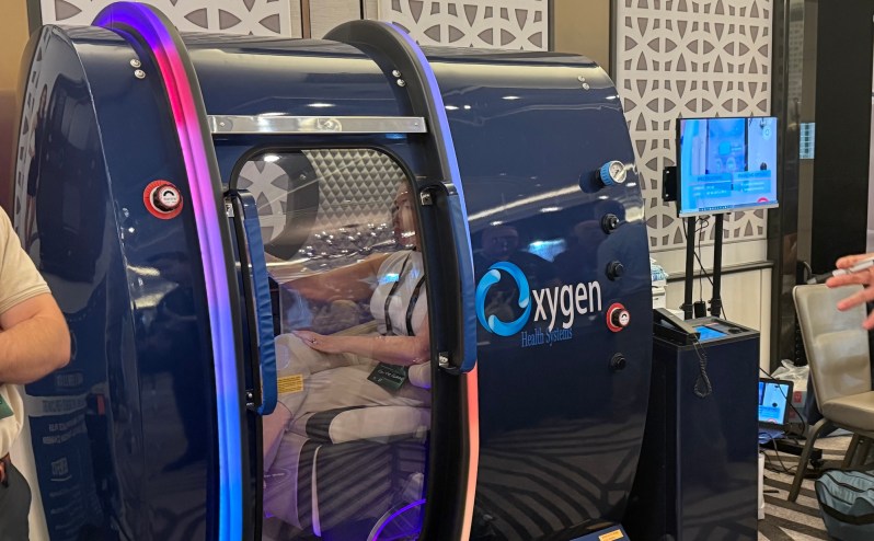 photo of a person sitting inside a blue hyperbaric chamber