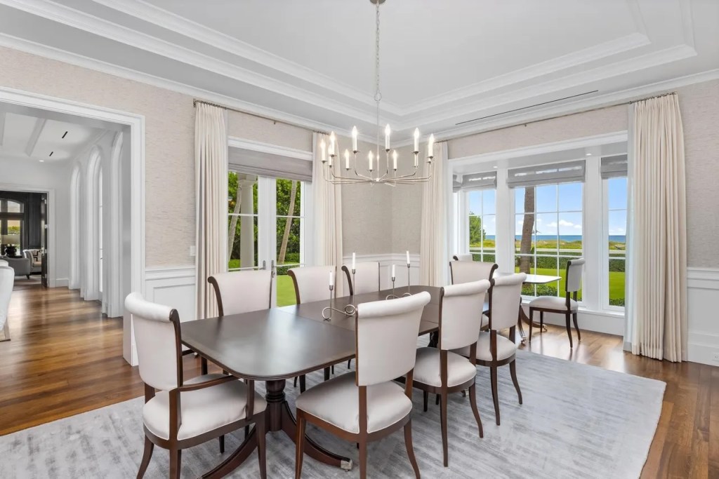 a wooden dining room table sits in the center of a white-and-beige dining room