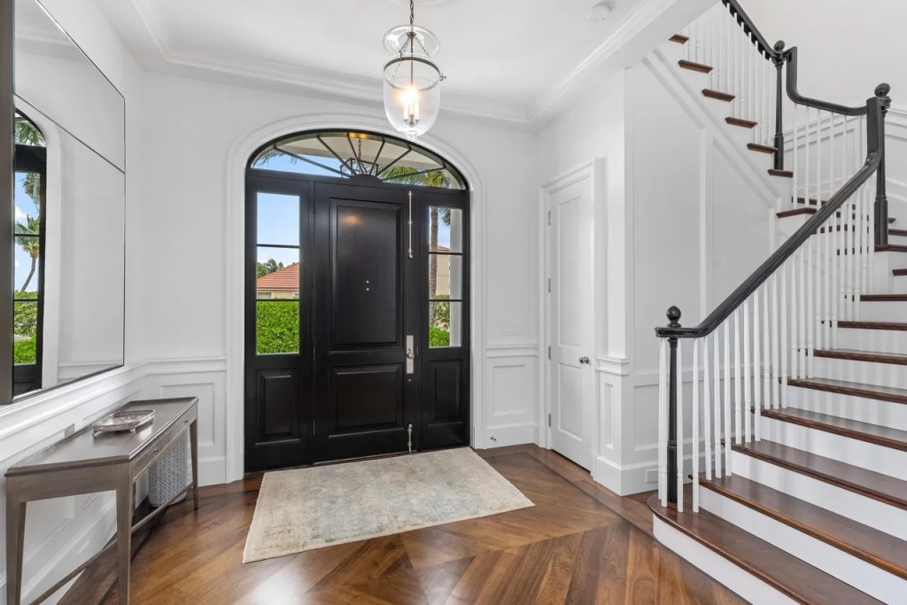 the entryway features a black door and black banister on a wooden staircase leading to the second floor