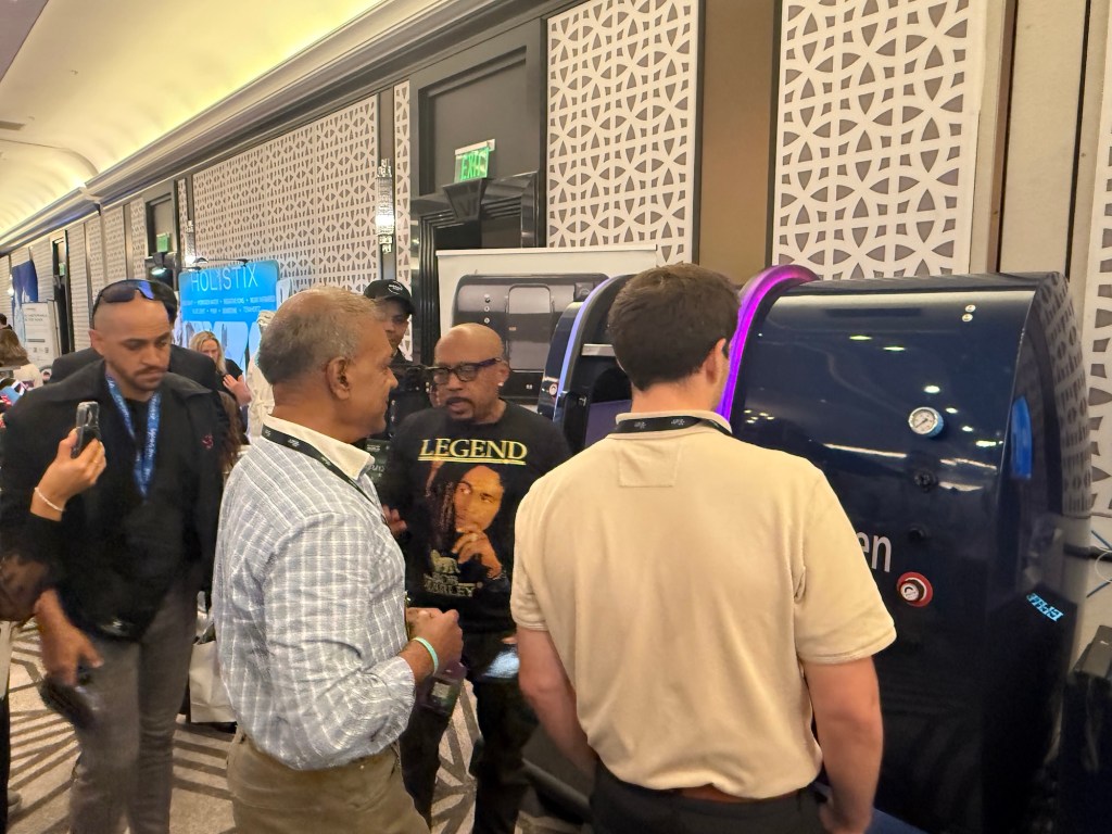 photo of Daymond John surrounded by people in front of a blue hyperbaric chamber