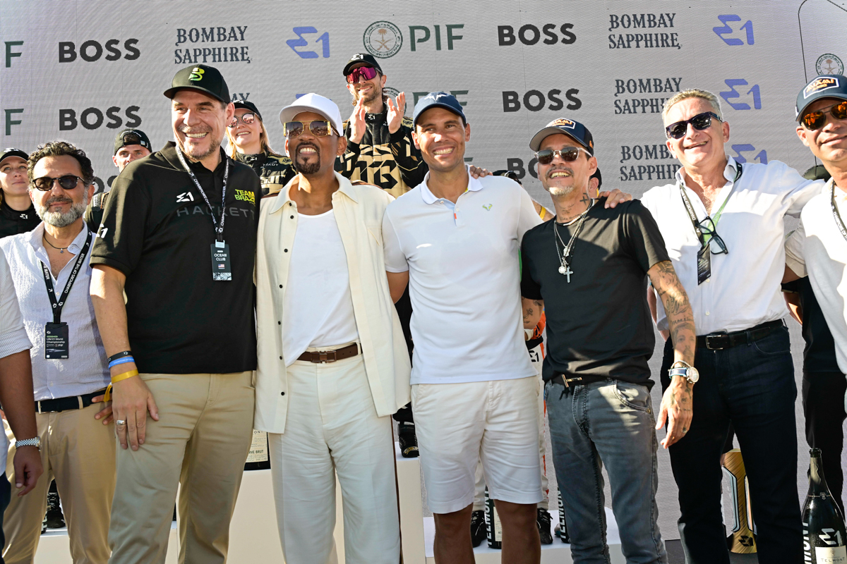 photo of six men posing in the foreground in front of an LED screen