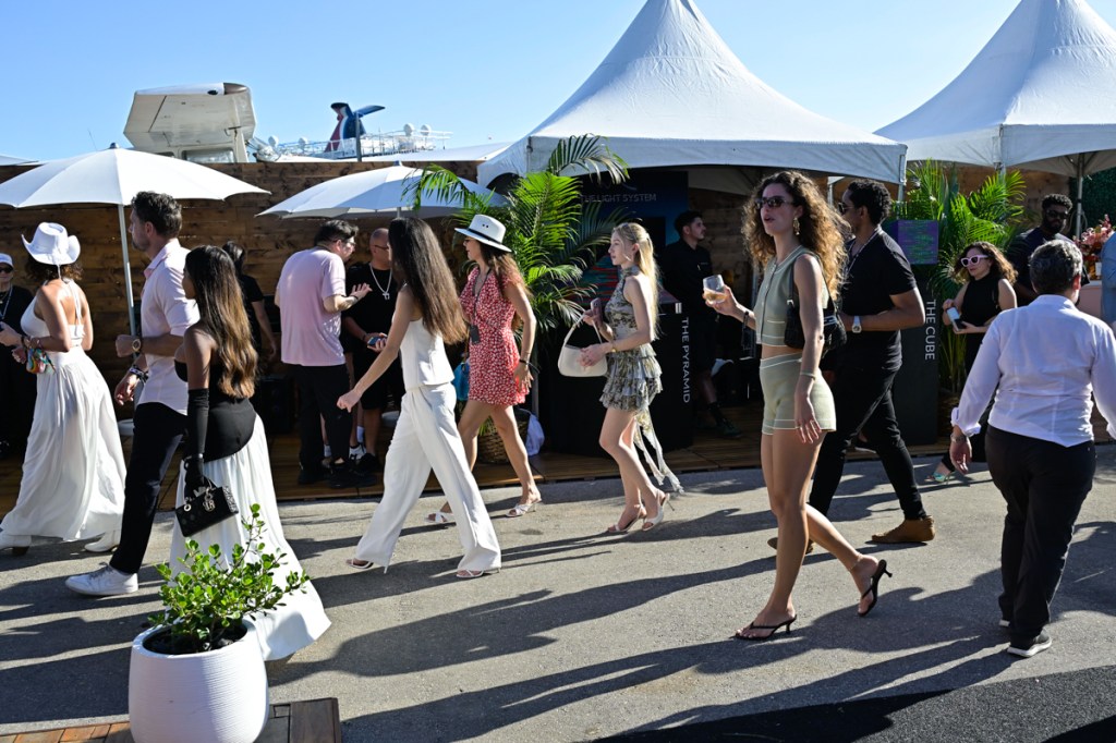 photo of a crowd of people walking through a thoroughfare in front of tented festival booths