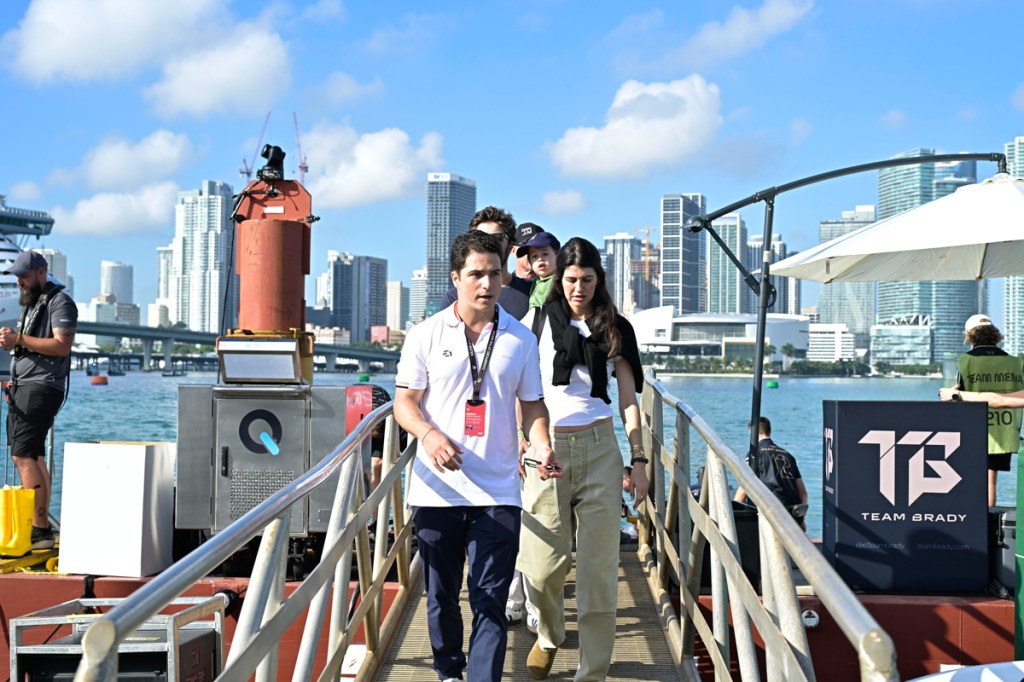 photo of a group of people walking between two platforms in front of the ocean with the Miami skyline in the background