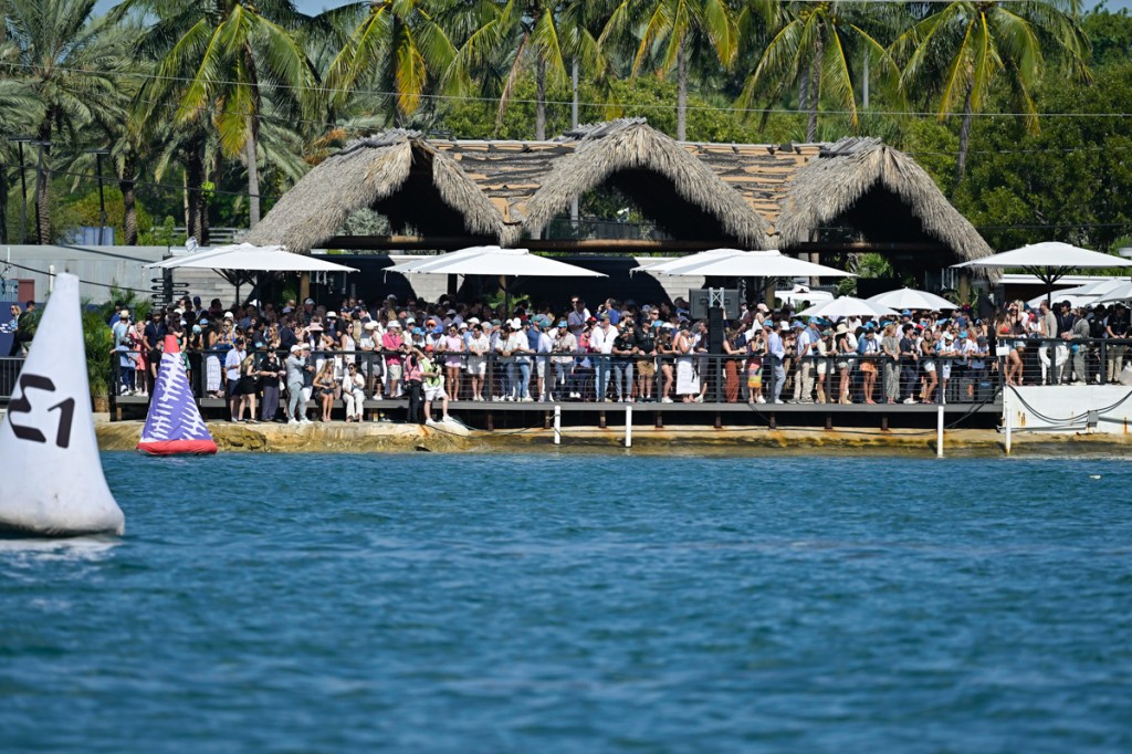 photo of a crowd gathered in front of a waterfront, tiki-style building