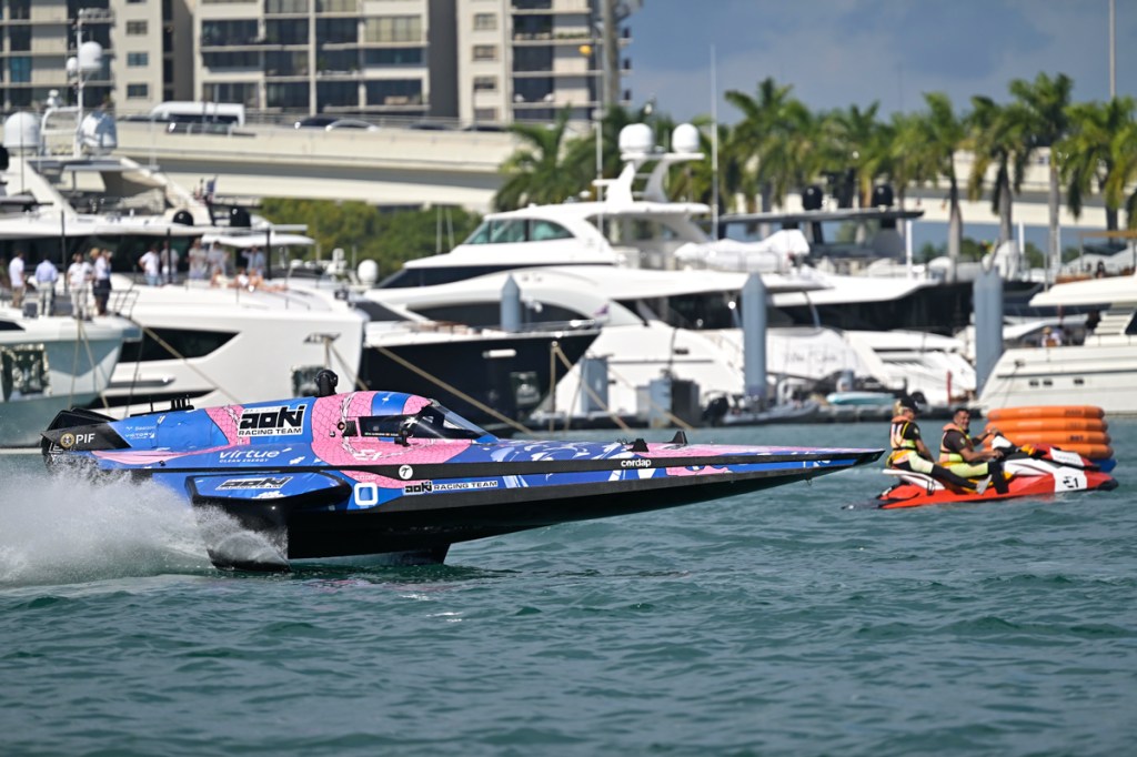 photo of a pink and blue powerboat skimming over the water in front of a marina