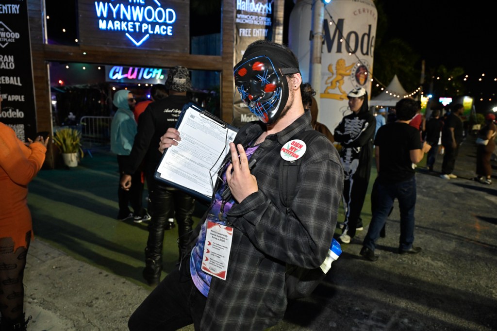 photo of a man in a Haloween costume holding a petition for marijuana legalization