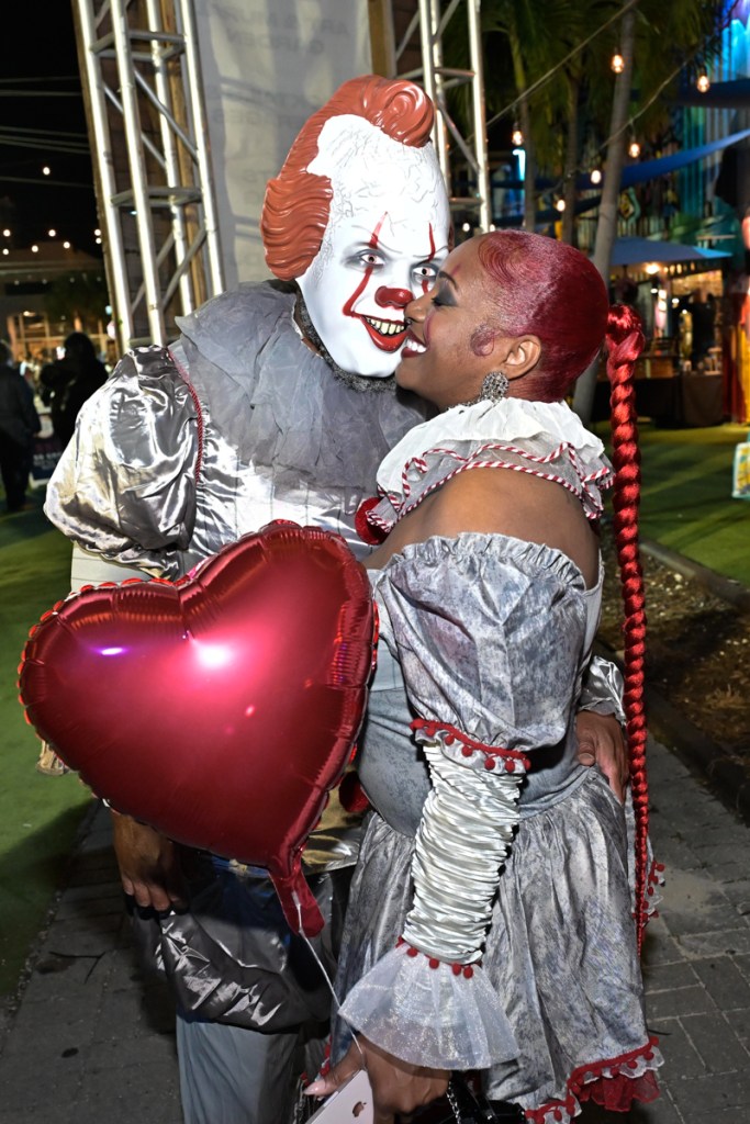 photo of a woman in a clown costume nuzzling with a person wearing a Pennywise costume