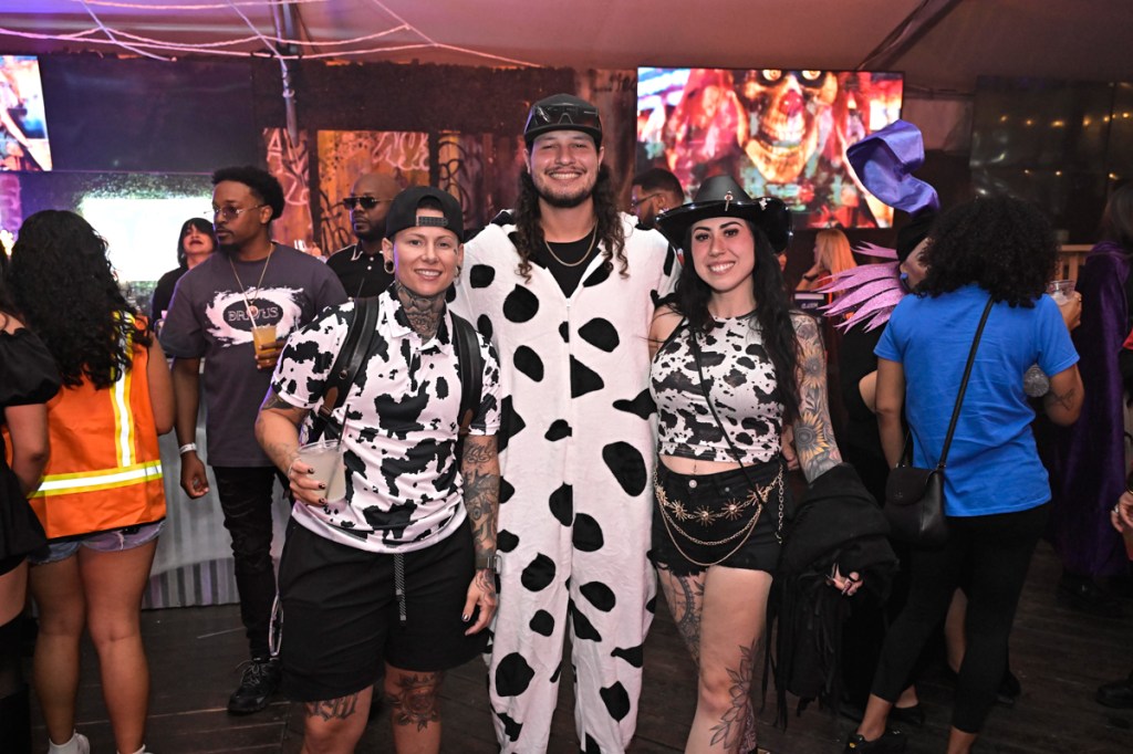 photo of three people dressed in cow print outfits