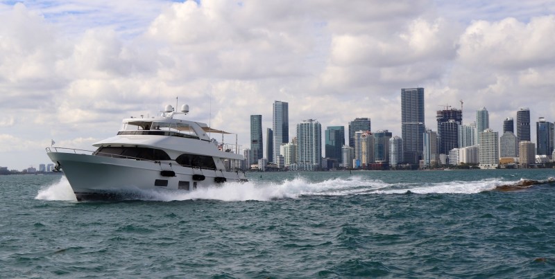 photo of a yacht cruising on the water with the Miami skyline behind it