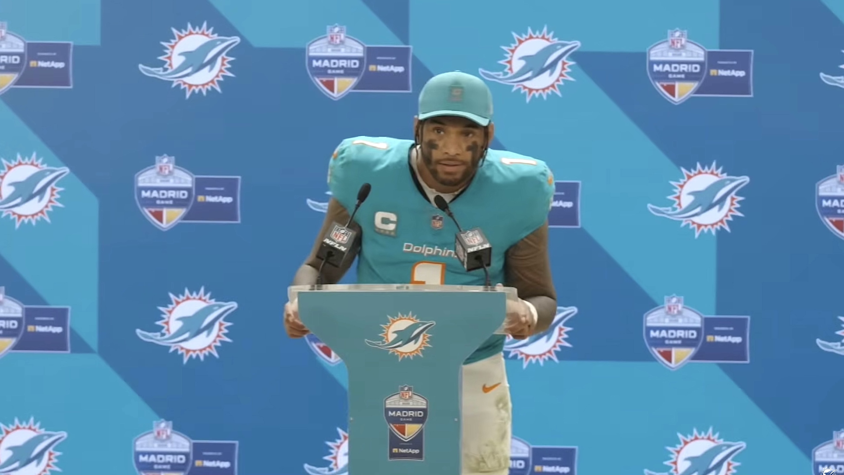 Miami Dolphins quarterback in uniform and speaking into microphone at press conference podium
