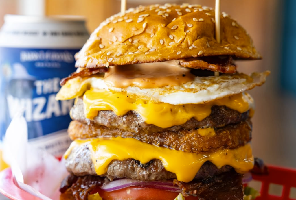 double cheeseburger with an egg and a soda to the side