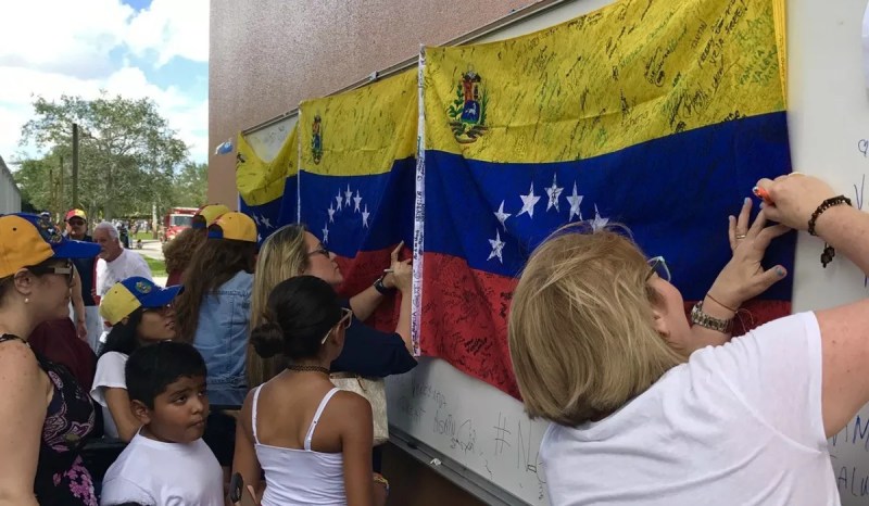 Photo of women signing Venezuelan flags at a demonstration.