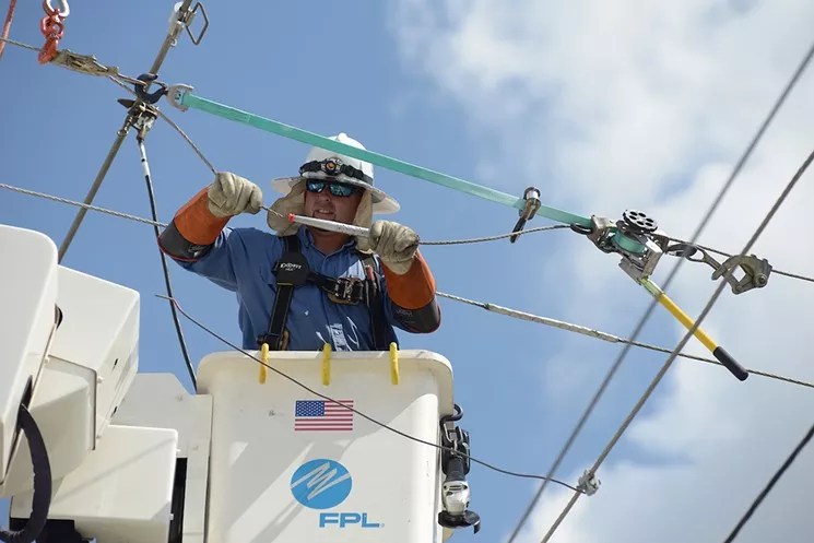 A utility employee works on a power line.