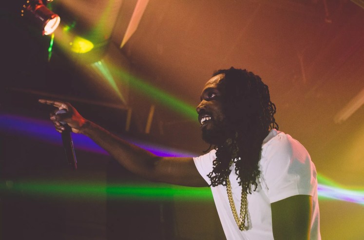 Picture of Jamaican singer Mavado on stage holding a microphone.