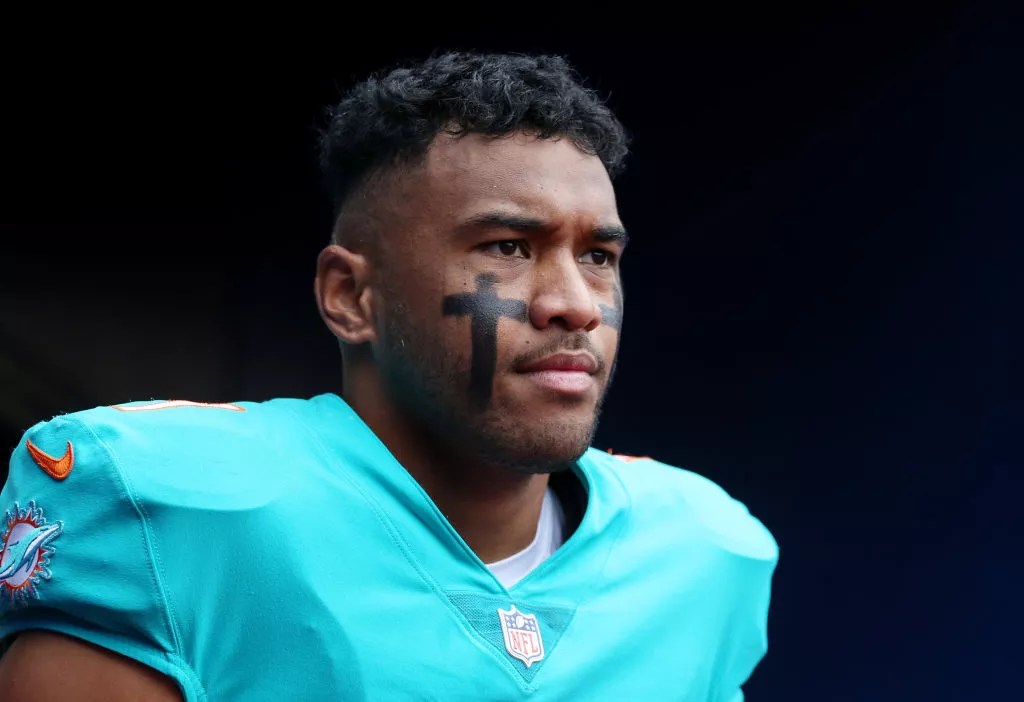 Tua Tagovailoa in pads without a helmet, looking  determined.