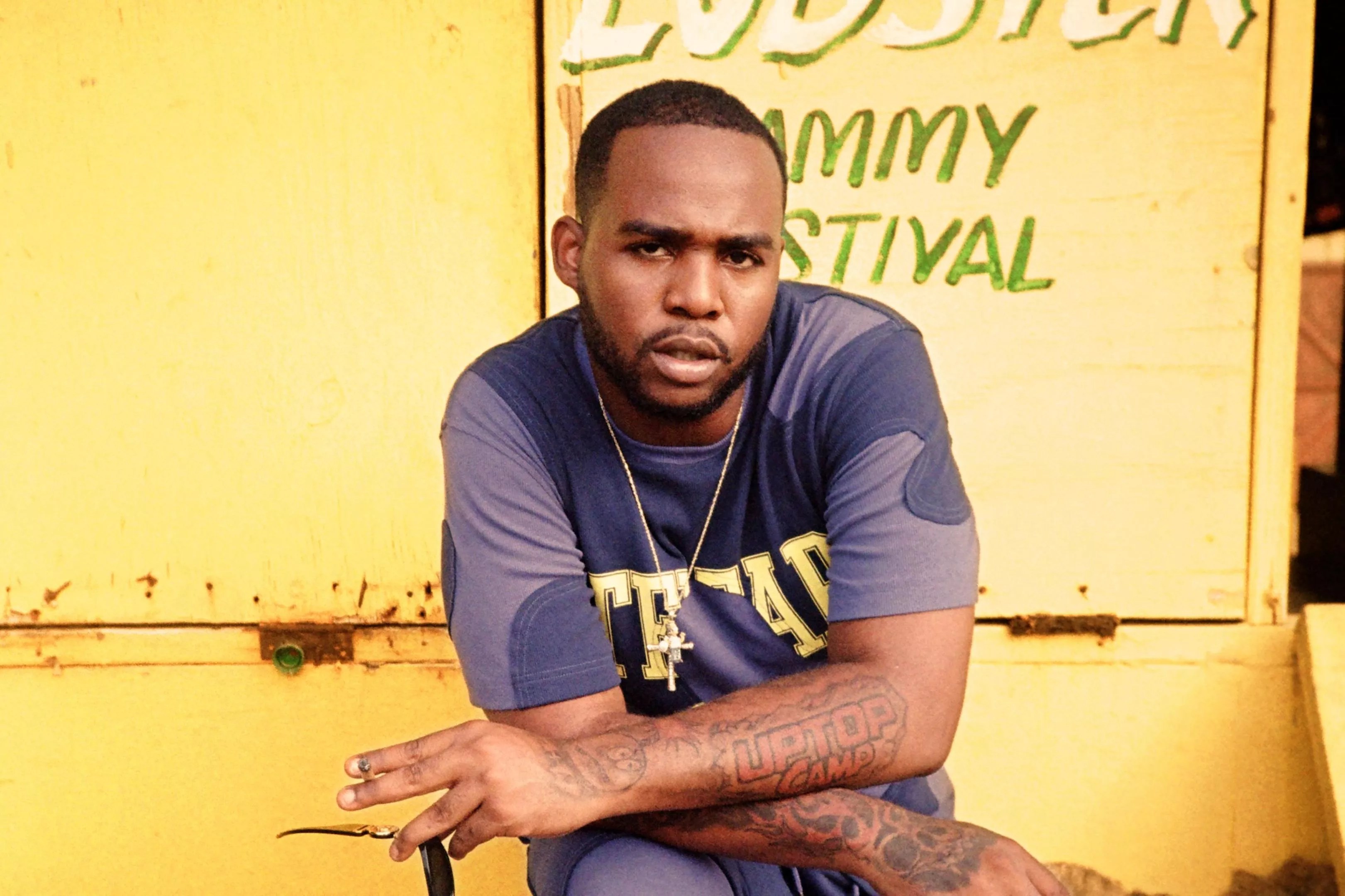 Dancehall singer Teejay with his arms cross against a yellow background
