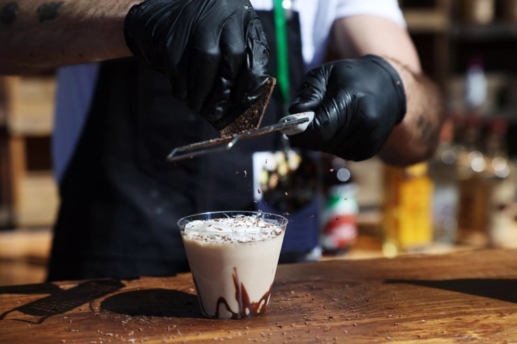 Hands shaving chocolate on drink