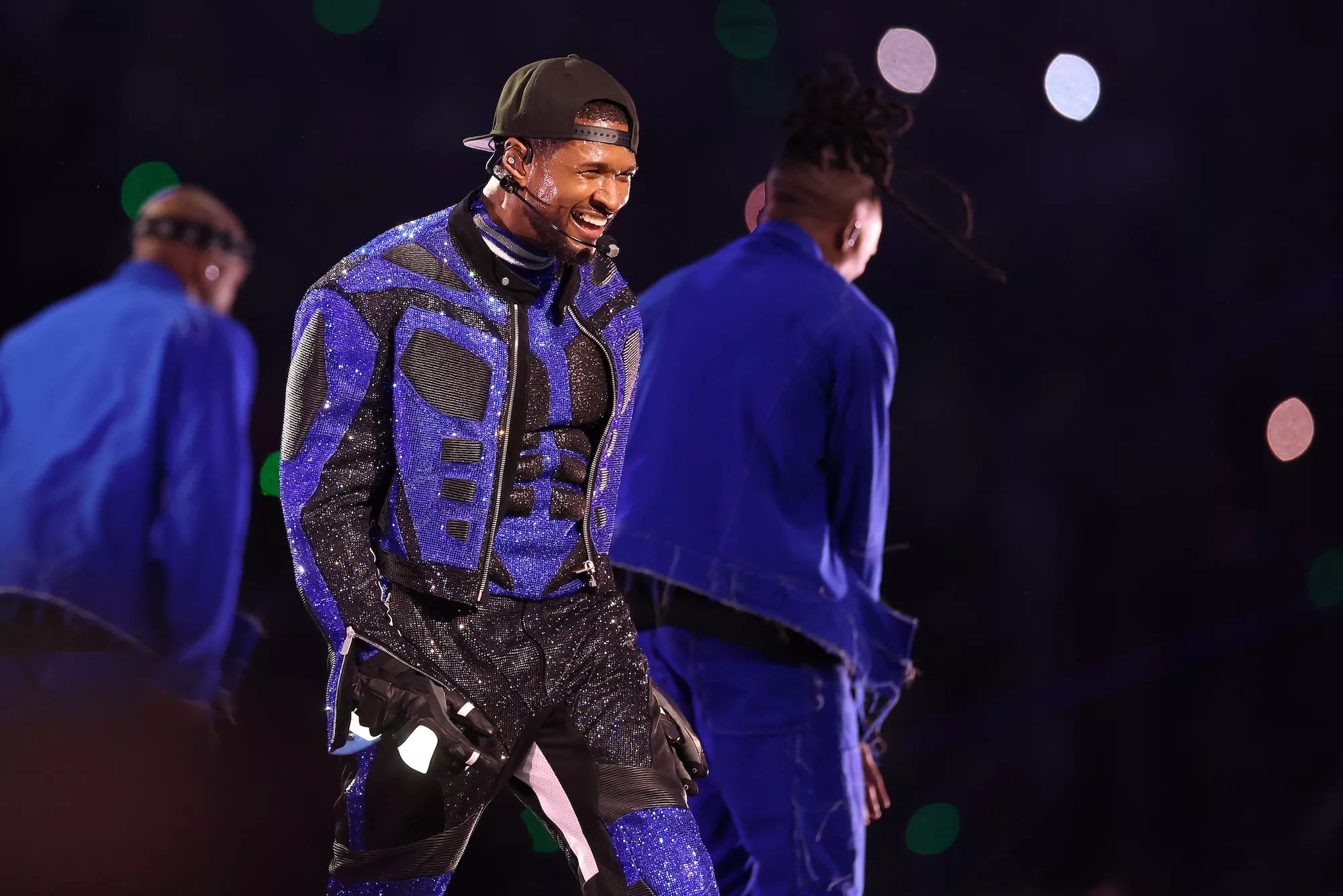 Usher performing onstage in a blue and black sequin outfit