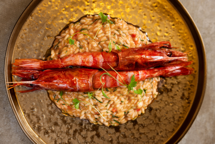 A rice dish with prawns in a gold setting