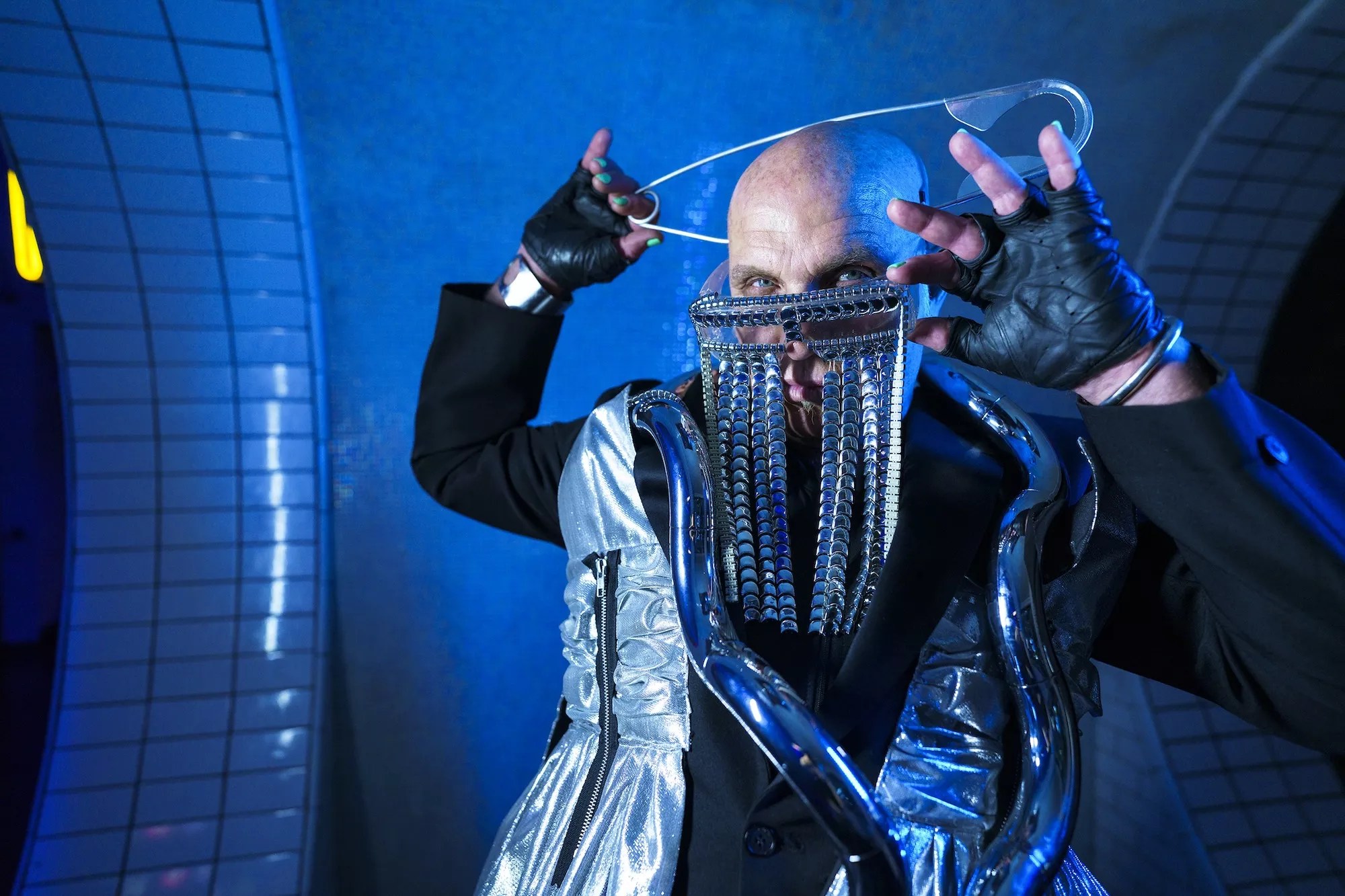 Alan T poses with a huge pin on his head and glasses with chains dropping down