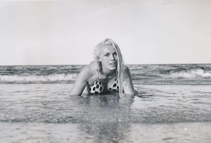 Bunny Yeager crawling out of the ocean onto the shore