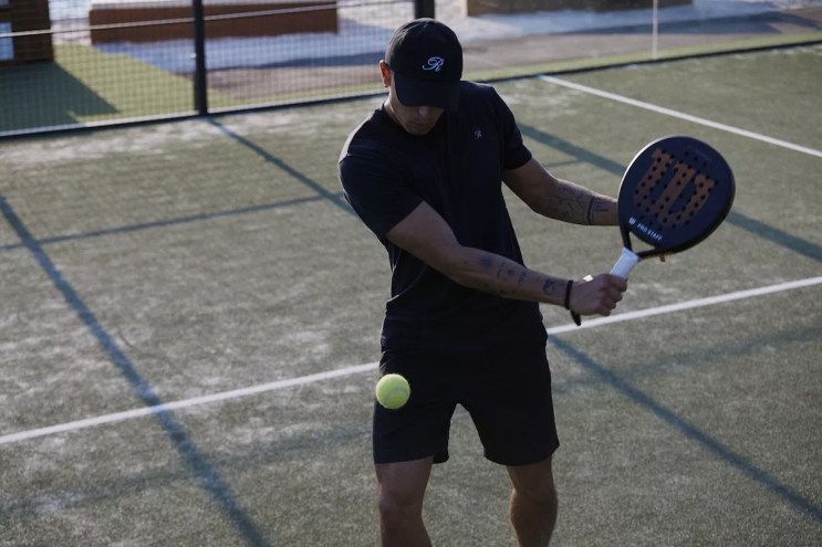 A man playing hitting a ball with a padel racket