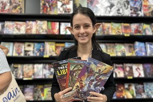 A woman with prosthetic ears holding comic books in her hands
