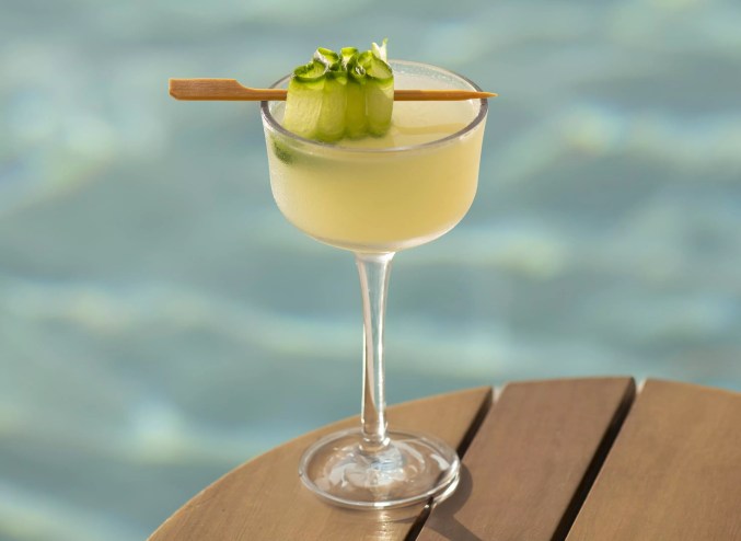 A yellow cocktail with a pool in the background